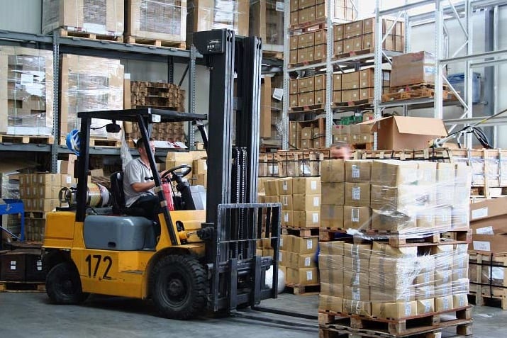 Forklift lifting pallets in a busy warehouse